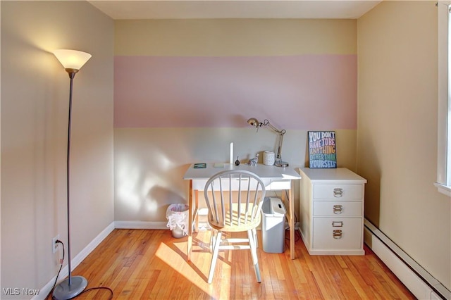 office space featuring light wood finished floors, baseboards, and a baseboard heating unit