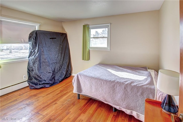 bedroom with a baseboard heating unit and wood finished floors