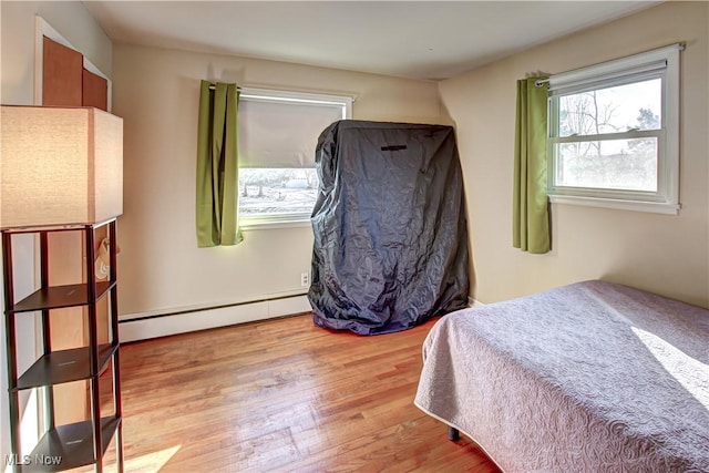 bedroom featuring a baseboard heating unit and wood finished floors