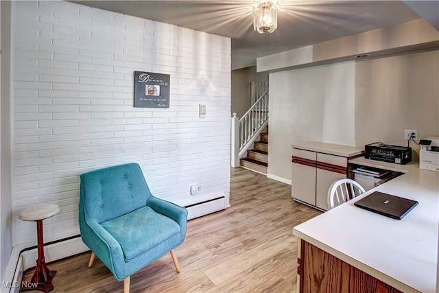 office space with brick wall, baseboard heating, and light wood-style flooring