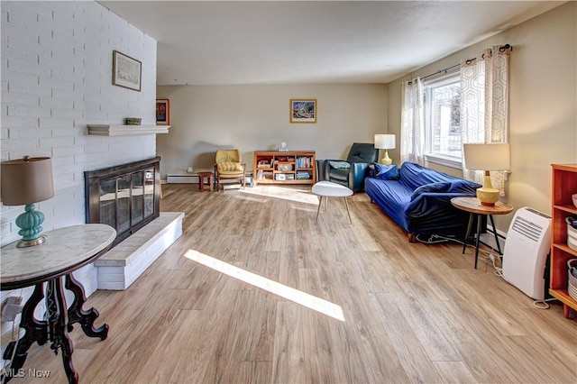 living room featuring a baseboard heating unit, a fireplace, baseboard heating, and wood finished floors