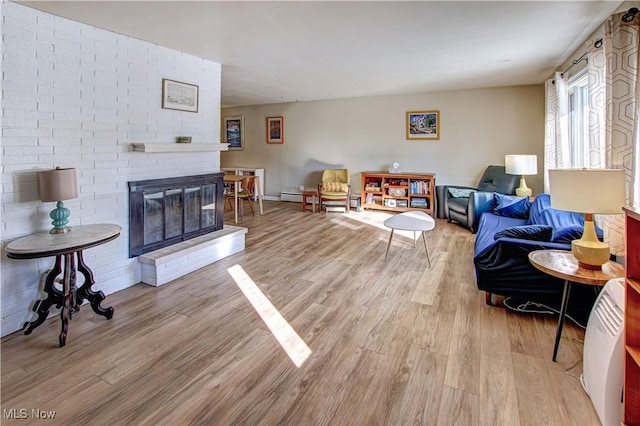 living area with a brick fireplace and wood finished floors