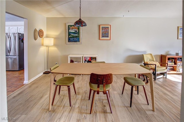 dining space with light wood-type flooring and baseboards