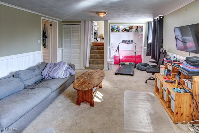 living room with carpet floors, wainscoting, crown molding, and stairs