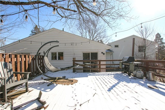 snow covered back of property featuring a deck