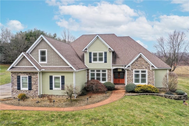 craftsman-style home with a shingled roof, stone siding, french doors, and a front lawn