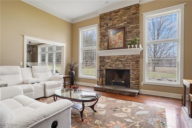 living room with a fireplace, crown molding, visible vents, wood finished floors, and baseboards