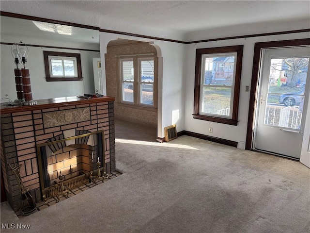 carpeted living room with baseboards, plenty of natural light, a fireplace, and crown molding