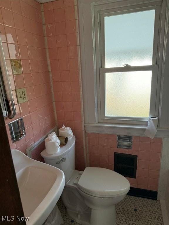 bathroom featuring a sink, tile walls, toilet, and tile patterned floors