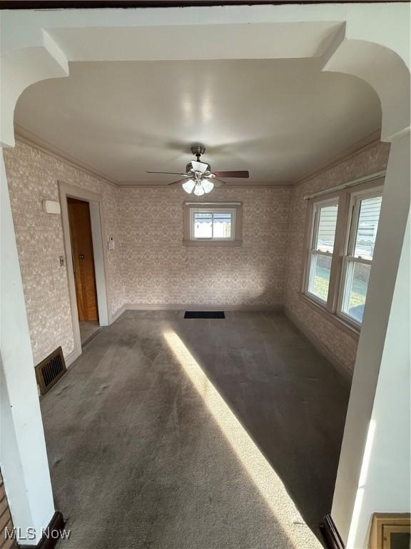 carpeted spare room with brick wall, ornamental molding, plenty of natural light, and visible vents