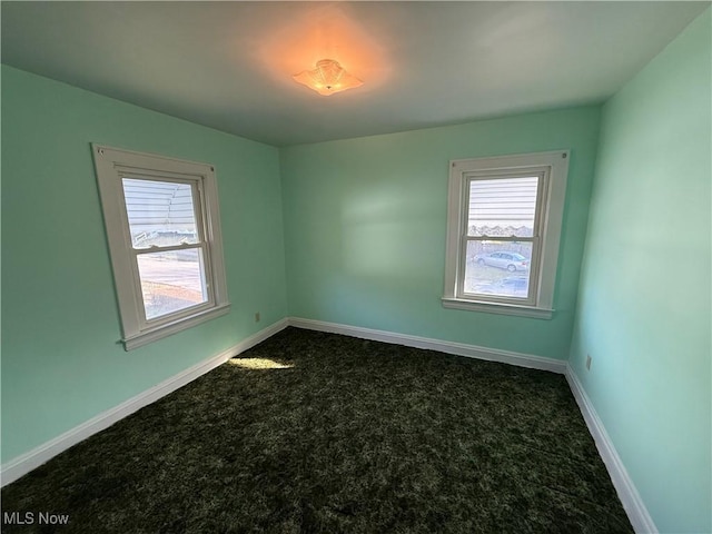 spare room with dark carpet and baseboards