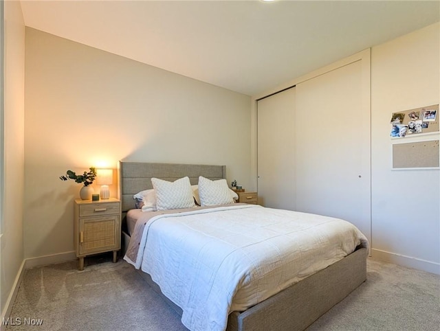 bedroom featuring a closet, light colored carpet, and baseboards