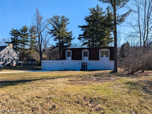 front facade with a front lawn, mansard roof, and concrete driveway