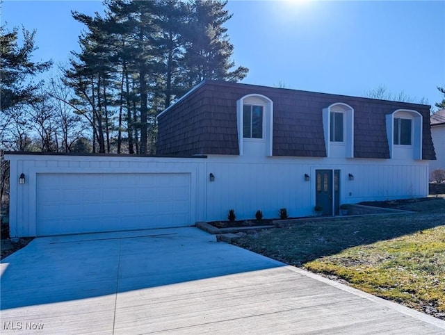 front of property with mansard roof, concrete driveway, and a garage