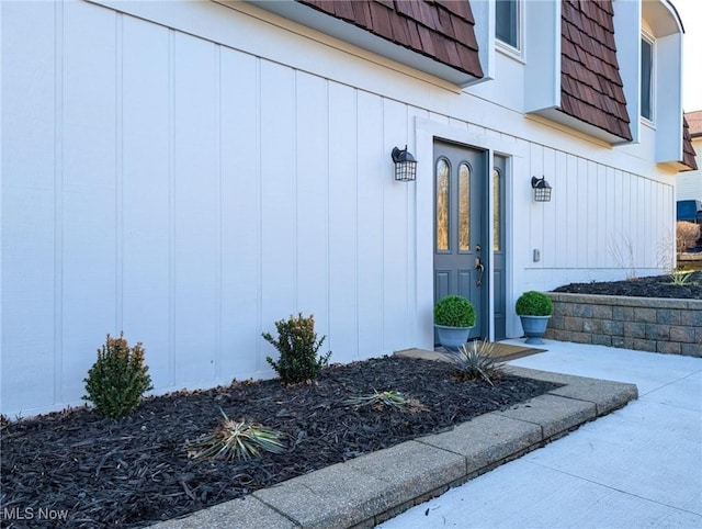 property entrance featuring mansard roof and board and batten siding