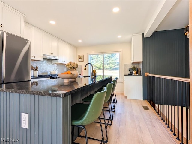 kitchen featuring decorative backsplash, white cabinetry, and a sink