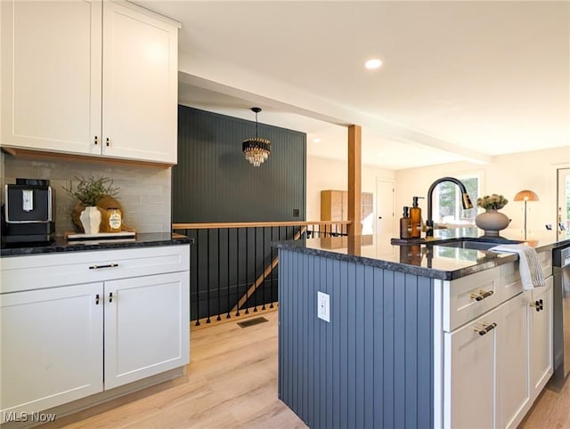 kitchen with visible vents, backsplash, a kitchen island, white cabinetry, and light wood finished floors