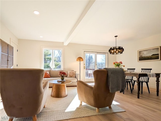 living room with beamed ceiling, plenty of natural light, light wood-style floors, and a chandelier