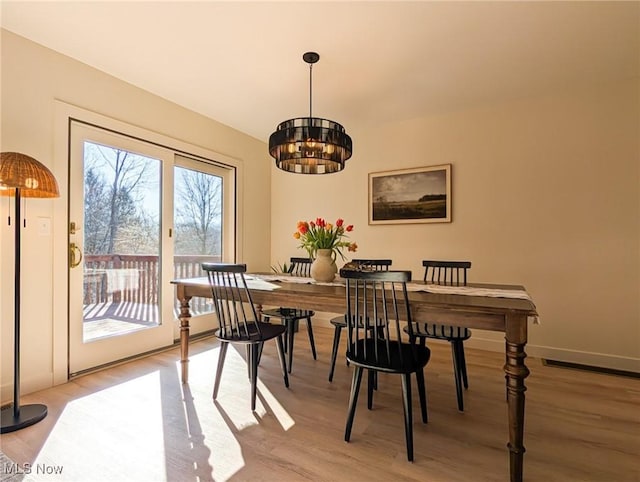 dining area with a notable chandelier, light wood-style floors, and baseboards