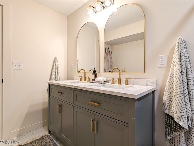 bathroom featuring a sink, baseboards, marble finish floor, and double vanity