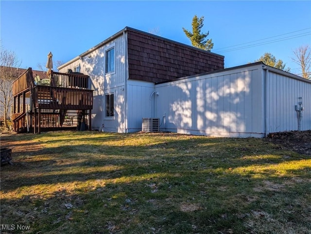 exterior space with a yard, mansard roof, central air condition unit, and stairs