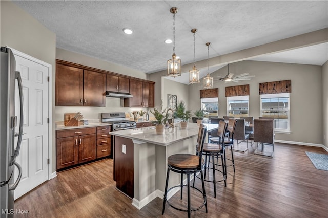 kitchen featuring dark wood finished floors, an island with sink, a kitchen breakfast bar, stainless steel appliances, and under cabinet range hood