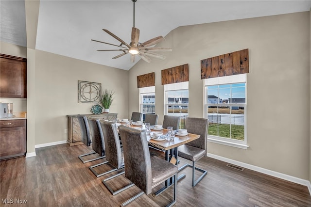 dining room with ceiling fan, dark wood-type flooring, visible vents, baseboards, and vaulted ceiling