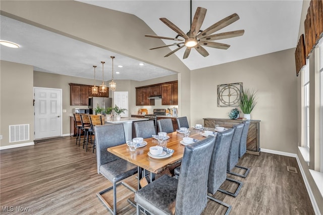 dining space with lofted ceiling, visible vents, baseboards, and wood finished floors