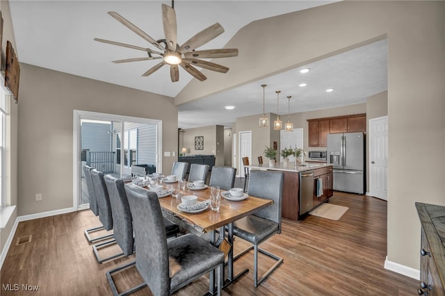 dining room featuring lofted ceiling, visible vents, baseboards, and wood finished floors