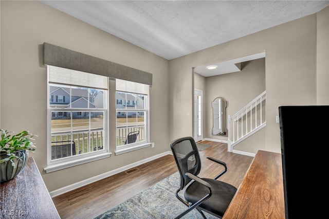 office area with baseboards, a textured ceiling, visible vents, and wood finished floors