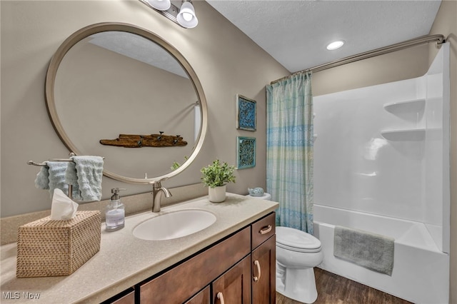 bathroom featuring a textured ceiling, toilet, wood finished floors, vanity, and shower / bath combo