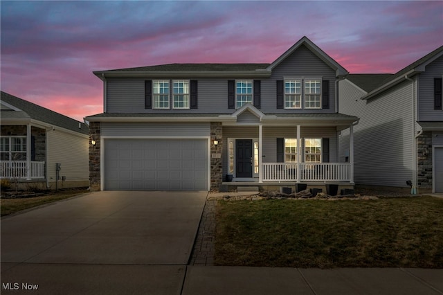 view of front facade with an attached garage, covered porch, stone siding, and concrete driveway