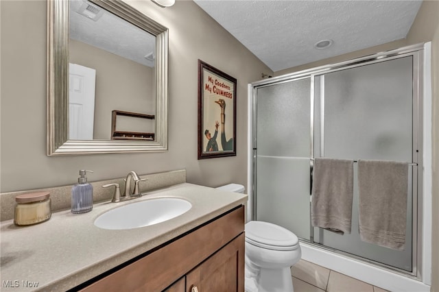 full bath with a textured ceiling, a stall shower, vanity, and toilet