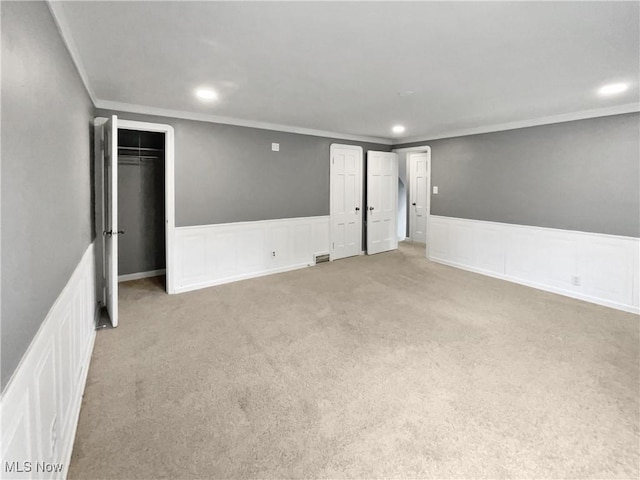 carpeted spare room featuring a wainscoted wall, visible vents, crown molding, and recessed lighting