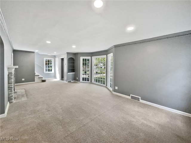 unfurnished living room featuring carpet, baseboards, stairway, and crown molding