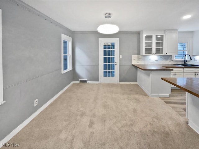 kitchen with visible vents, dark countertops, glass insert cabinets, white cabinetry, and a sink