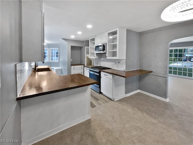 kitchen featuring range with gas stovetop, stainless steel microwave, backsplash, a sink, and butcher block countertops