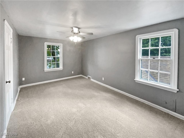 carpeted empty room featuring visible vents, baseboards, and a ceiling fan