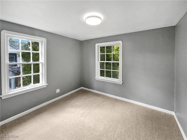 carpeted empty room featuring baseboards