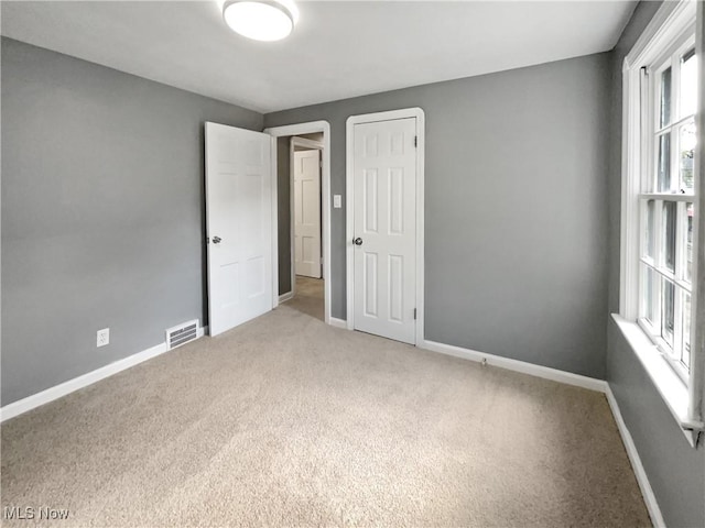 spare room with carpet floors, visible vents, and baseboards