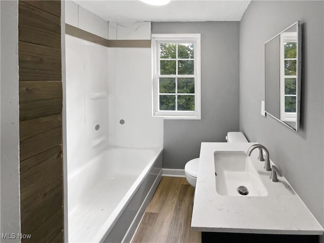 full bath featuring baseboards, toilet, vanity, wood finished floors, and shower / bathtub combination