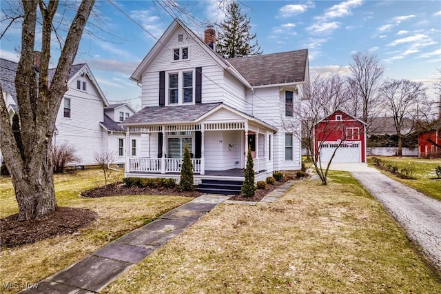 victorian-style house featuring a porch, a front yard, a detached garage, and a chimney