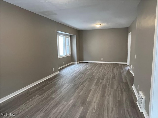 spare room with visible vents, dark wood finished floors, and baseboards