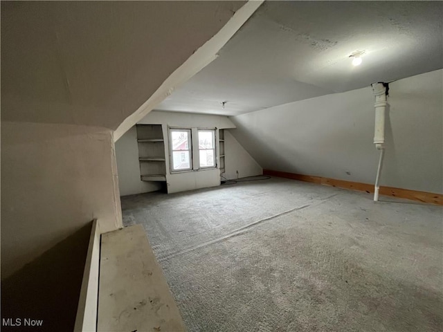 bonus room featuring vaulted ceiling and carpet