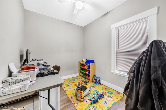 recreation room featuring a ceiling fan, baseboards, and wood finished floors