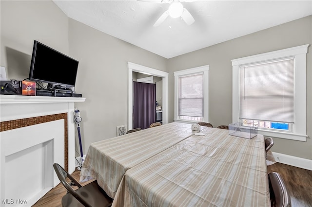 bedroom featuring dark wood-type flooring, a fireplace, ceiling fan, and baseboards