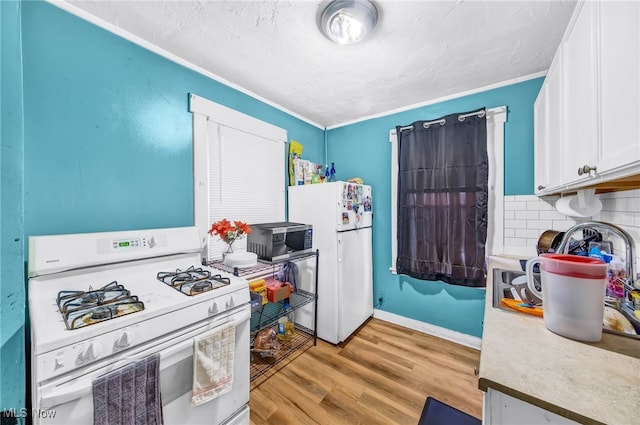 kitchen with light wood-style flooring, white appliances, baseboards, white cabinets, and backsplash