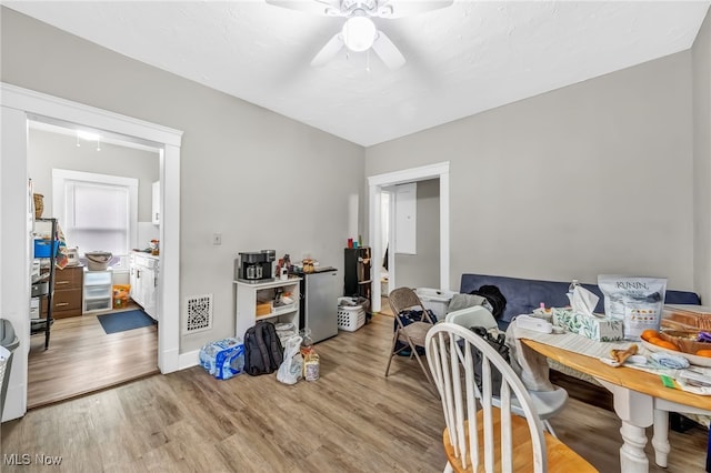 interior space with a ceiling fan, visible vents, and wood finished floors