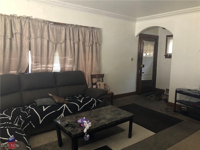 carpeted living area featuring ornamental molding, arched walkways, and baseboards