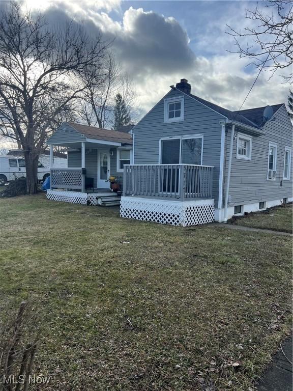 back of house with a deck and a lawn